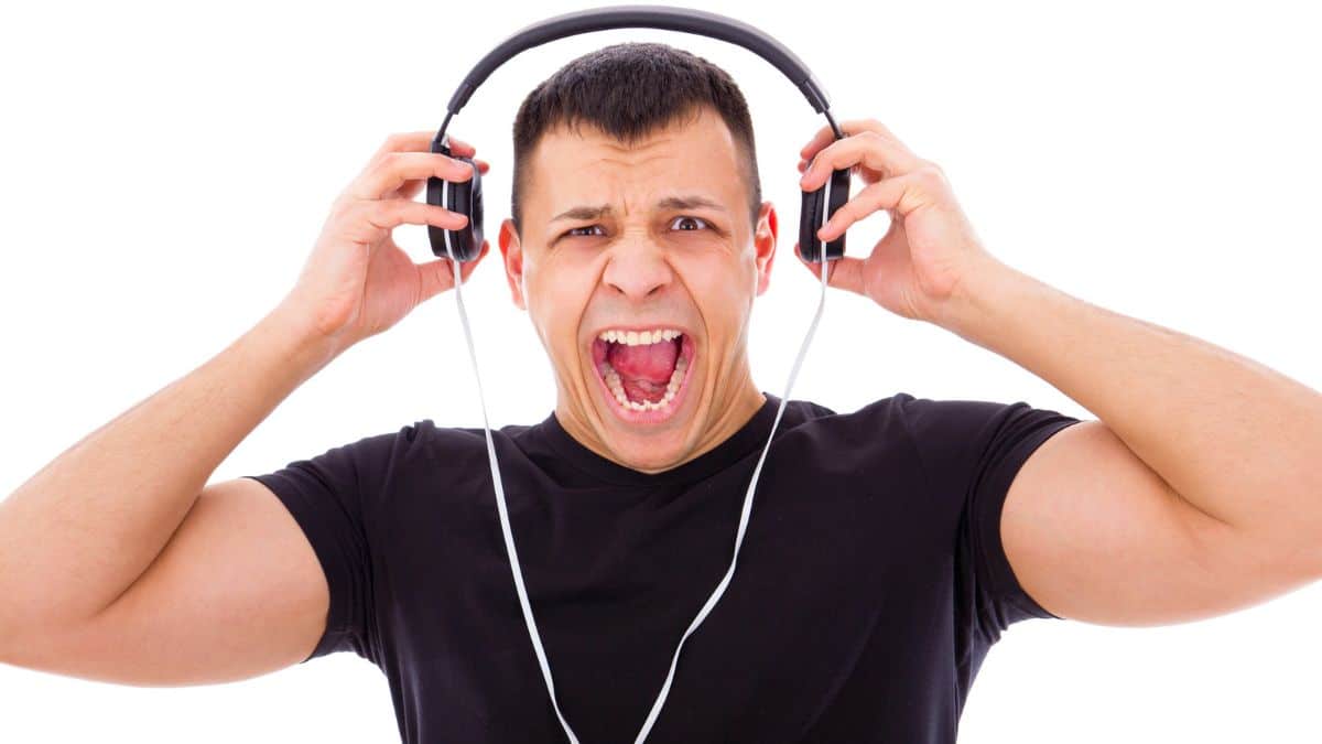 Man screaming with headphones on. Wearing a back tshirt.