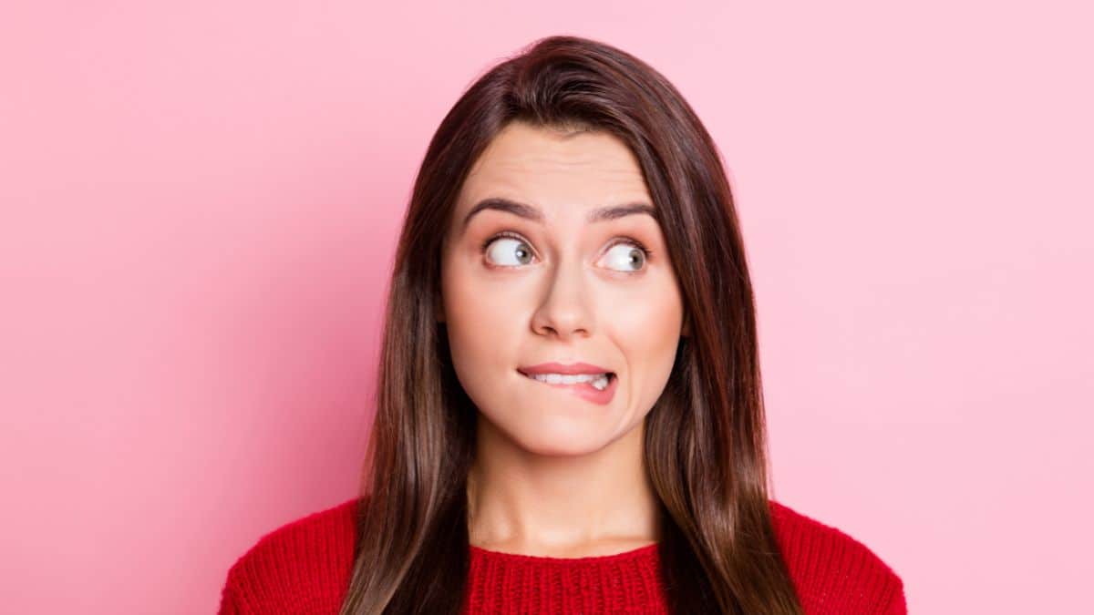 Woman looking uncomfortable eyes looking to the side. Pink background