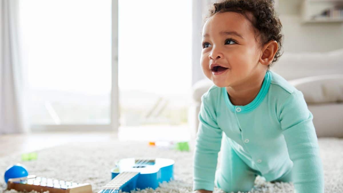 baby boy crawling and smiling in a blue onesie