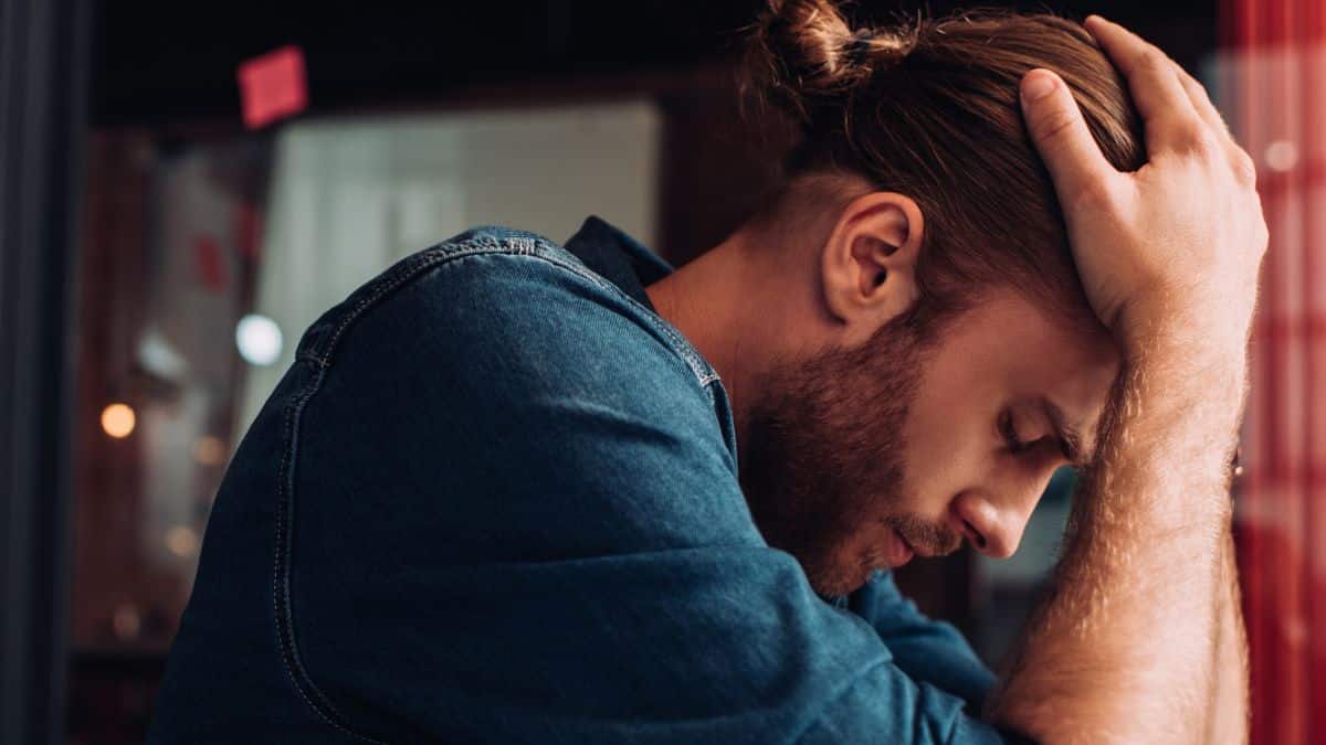 Man sitting upset with his hands over his head. Side view