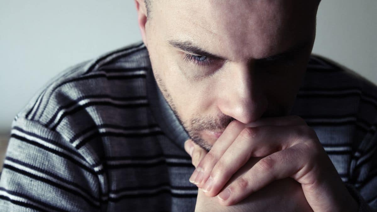 upset man looking down with hands on his mouth