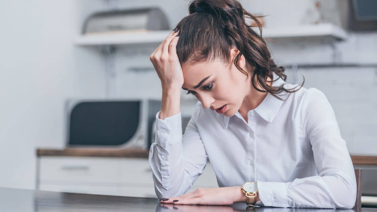 woman stressed out looking down with her hand on her head