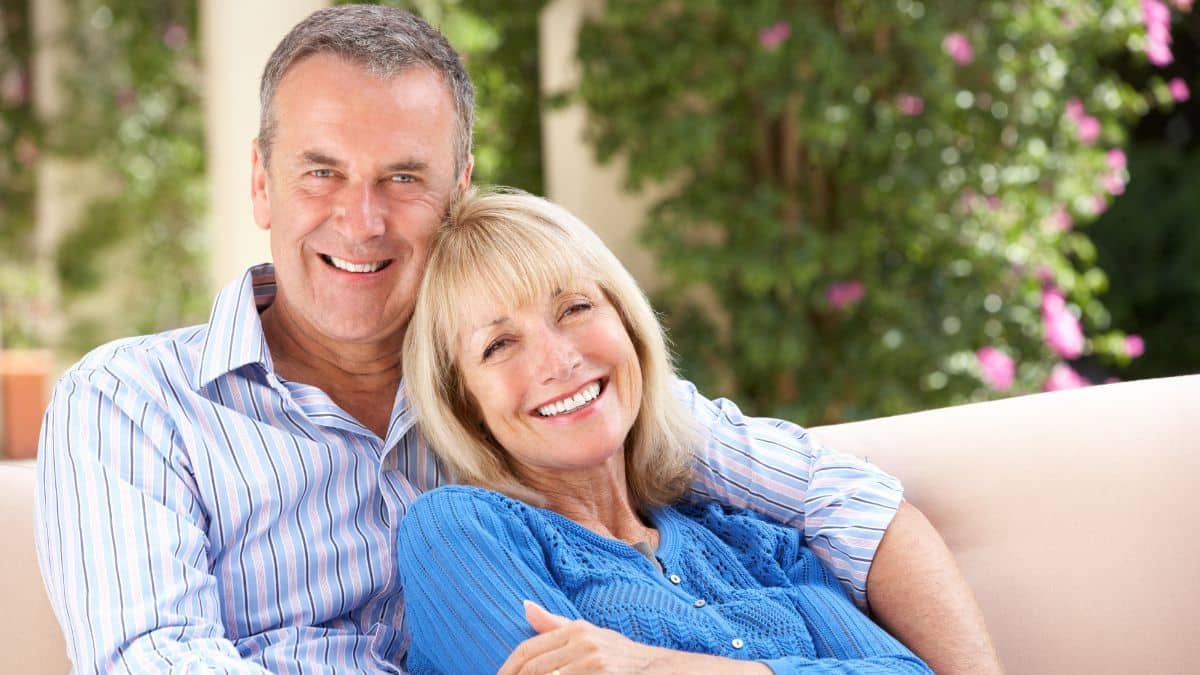 happy older couple sitting on the couch smiling and snuggling