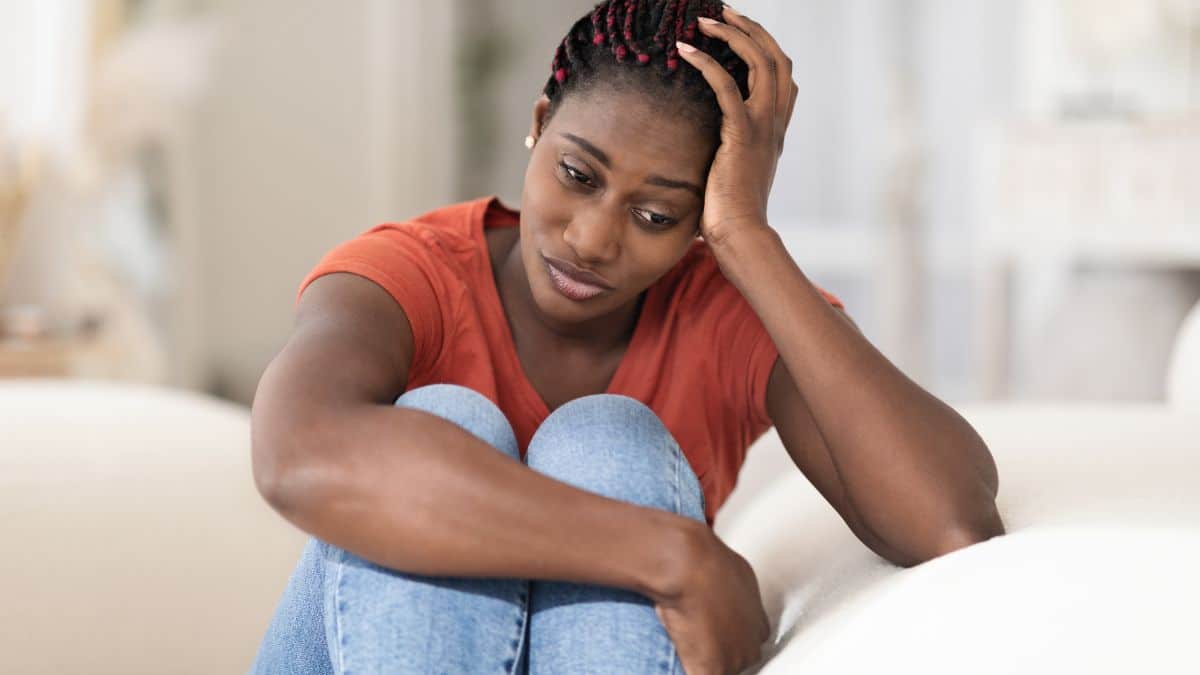 woman looking upset sitting with her head on her hand