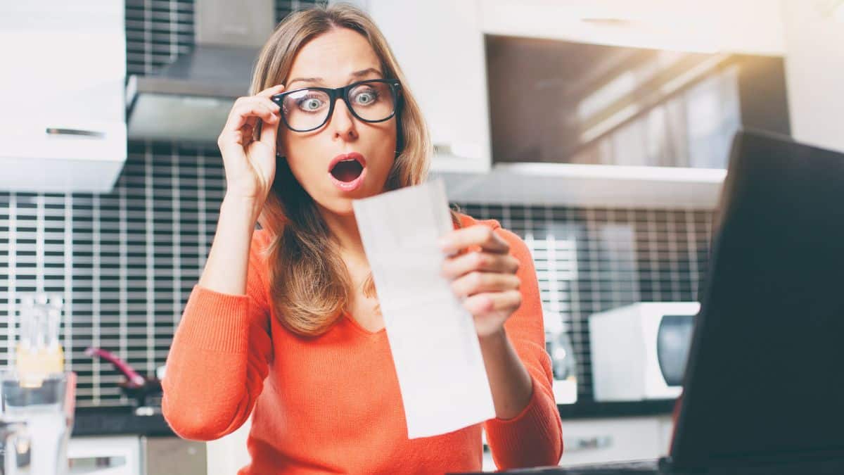 Woman looking at grocery bill in shock Image Credit Depositphotos