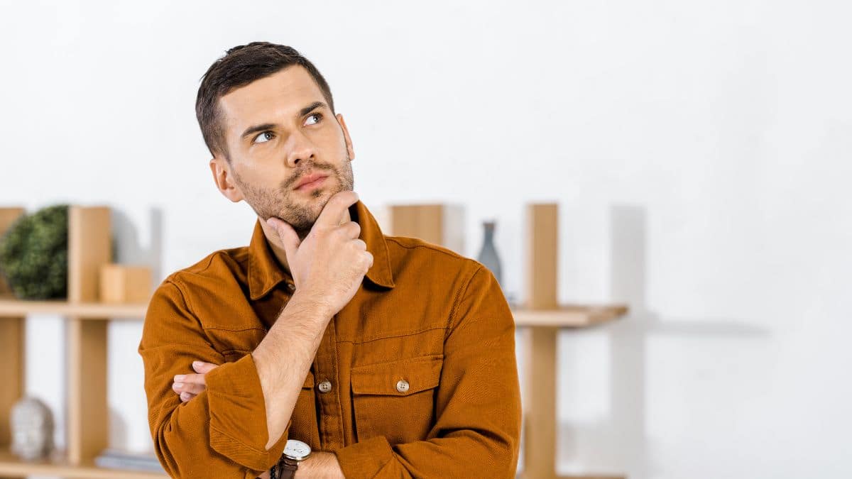 man thinking with hand on his chin looking up to the side arms crossed