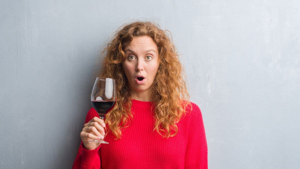 Woman holding wine looking surprised