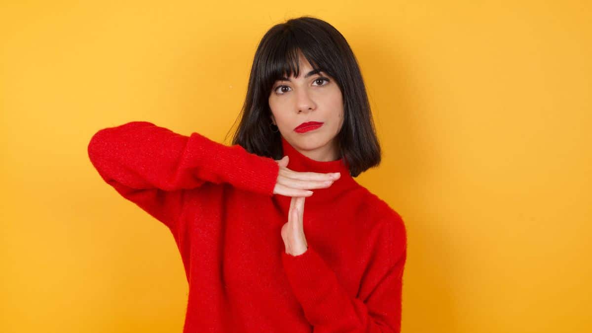 Woman wearing a red sweater signalling ing time out