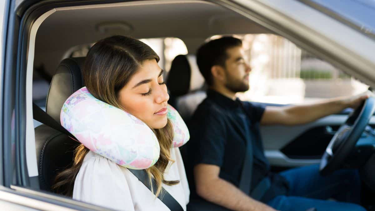 woman with travel pillow sleeping in car